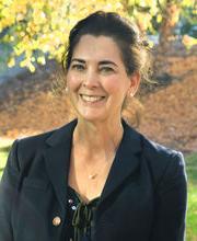 Dr. Kathleen Ferris with long dark hair pulled back wearing a black blazer over a black top