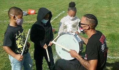 Greg Fernandes gives a drum lesson to three kids.