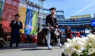 A student shows excitement as he crosses the commencement stage.